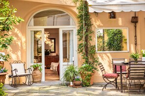 A cozy patio with a dining area, a seating arrangement, and a view of the interior through an open doorway.
