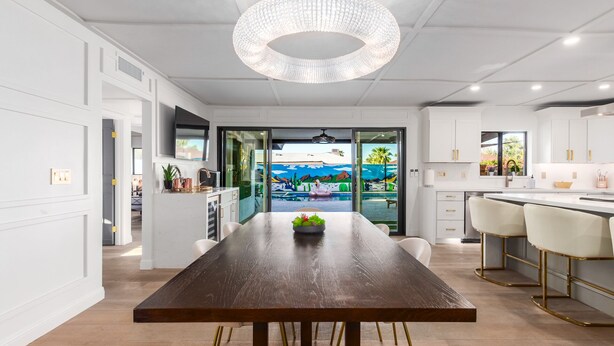 A modern kitchen with white cabinets, a wooden dining table, and a view of a pool through glass doors. - The Rody - Mins to Old Town with Heated Pool, Games, Fast Wifi and More... (Scottsdale)