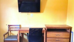 A room with a wooden desk, a chair, a television mounted on the wall, and a wooden dresser. - Relax Inn By OYO Sulphur Hwy 90 (Sulphur)