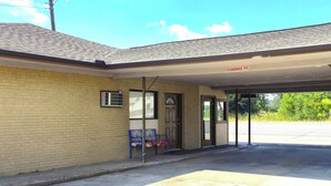 A building with a covered entrance, a sign indicating a 7ft clearance, and a bench outside. - Relax Inn By OYO Sulphur Hwy 90 (Sulphur)