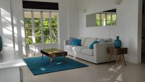Een moderne woonkamer met een witte bank, een bijzettafeltje en een blauw vloerkleed.