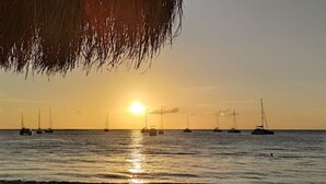 Een zonsondergang boven een rustige zee, met verschillende zeilboten.