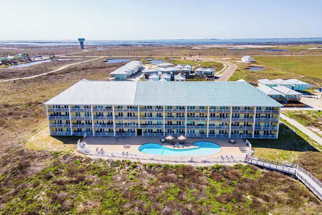 A large hotel with multiple floors, a swimming pool, and a view of the surrounding landscape.