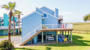 A two-story blue house with a wooden deck and outdoor seating area.