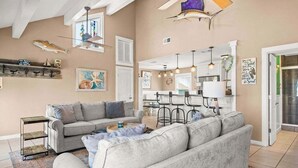 A spacious living area with a gray sofa, a coffee table, and a dining area with bar stools.