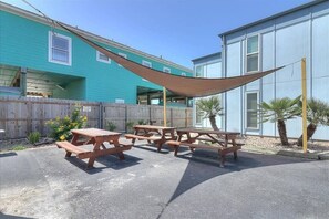 A patio area with picnic tables and a shade sail. - Pompano- 2 Min Drive to Beach! | Sleeps 4 (Port Aransas)