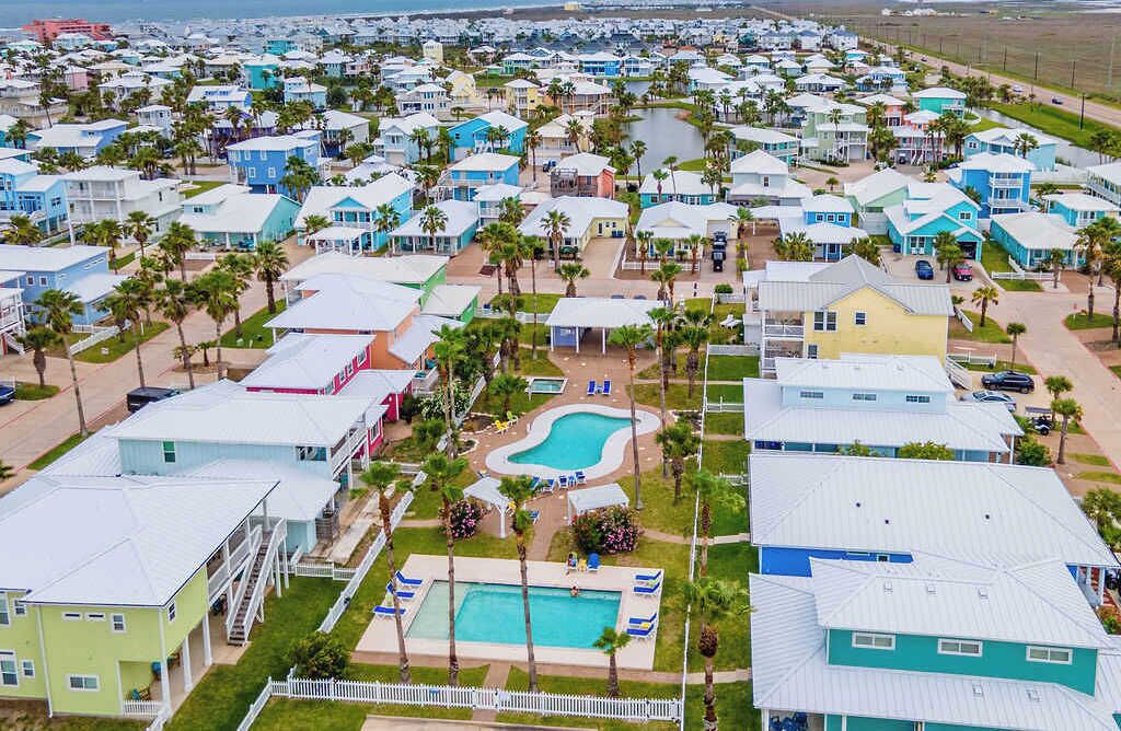 A coastal residential area with houses, a swimming pool, and palm trees.