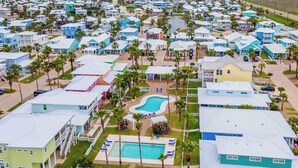 Uma área residencial costeira com casas, piscina e palmeiras.