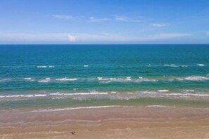 Une plage avec une eau d’un bleu limpide et un rivage sablonneux.