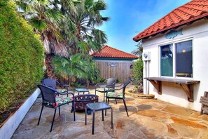 A patio with stone flooring, outdoor furniture, and a wooden fence. - Cozy Private Cottage~Pet Friendly~Prime Location (Port Aransas)