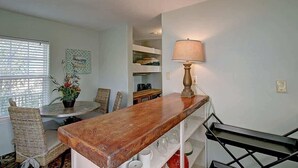 Un coin repas avec une table ronde, des chaises en osier, une plante en pot et une lampe.