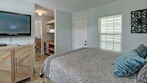 Une chambre à coucher avec un lit, une télévision, une armoire et une fenêtre avec des stores.