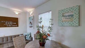 Un salon avec une table ronde, un canapé et un mur orné de citations inspirantes.