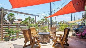 Une terrasse extérieure avec des chaises en bois et une table ronde, entourée d’une clôture en bois et de palmiers.