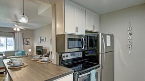 Una cocina con gabinetes blancos, electrodomésticos de acero inoxidable, una isla de madera y un ventilador de techo.