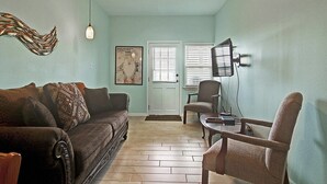 Ein Wohnzimmer mit Sofa, Sesseln, Deckenventilator und Fernseher.