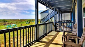 Eine überdachte Veranda mit Blick auf eine Rasenfläche und ein Gebäude im Hintergrund.