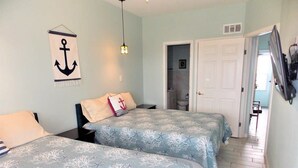 Ein Schlafzimmer mit zwei Betten, einem an der Wand hängenden Anker und einer Tür zu einem Badezimmer.