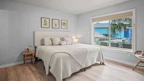 Une chambre à coucher avec un lit, une table de chevet, une fenêtre donnant sur un beau paysage et un luminaire au plafond.