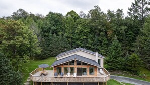Een huis met een terras, omringd door dicht bos.