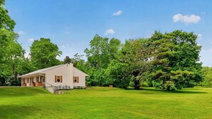 A single-story house with a porch, surrounded by a well-maintained lawn and large trees. - The Gate  -  Bungalow (Skaneateles)