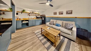 Una sala de estar moderna con un sofá, una mesa de centro y una cocina al fondo.