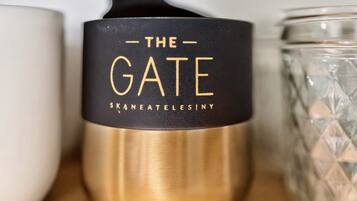 Una vela con tapa negra y detalles dorados, etiquetada 'THE GATE SKANEATLESINY'.