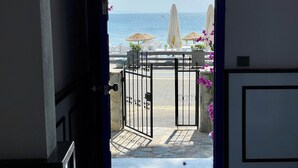 A view from a room through an open door to a beach area with umbrellas and lounge chairs. - Villa Ece Pension (Erdek)