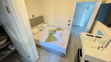 A small, clean room with a bed, a bedside table, and a TV.