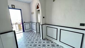 Un couloir avec des carreaux de sol à motifs, des murs blancs et des moulures noires.