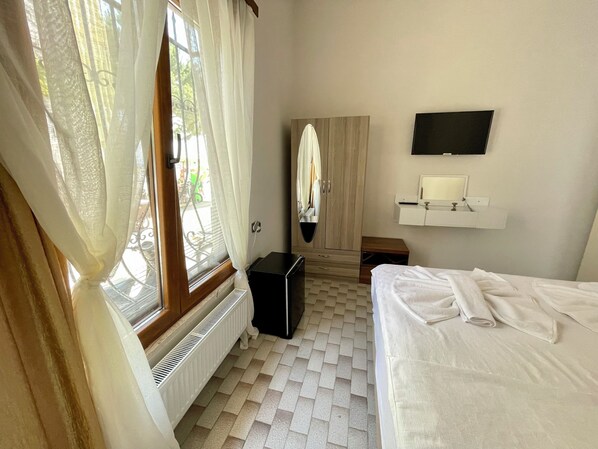 Une chambre d’hôtel équipée d’un lit, d’un radiateur, d’une armoire, d’un miroir et d’une télévision.