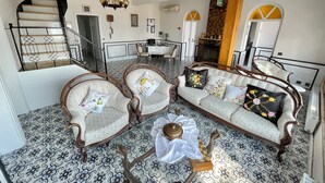 A spacious living area with a patterned floor, a sofa set, a coffee table, and a staircase. - Villa Ece Pension (Erdek)