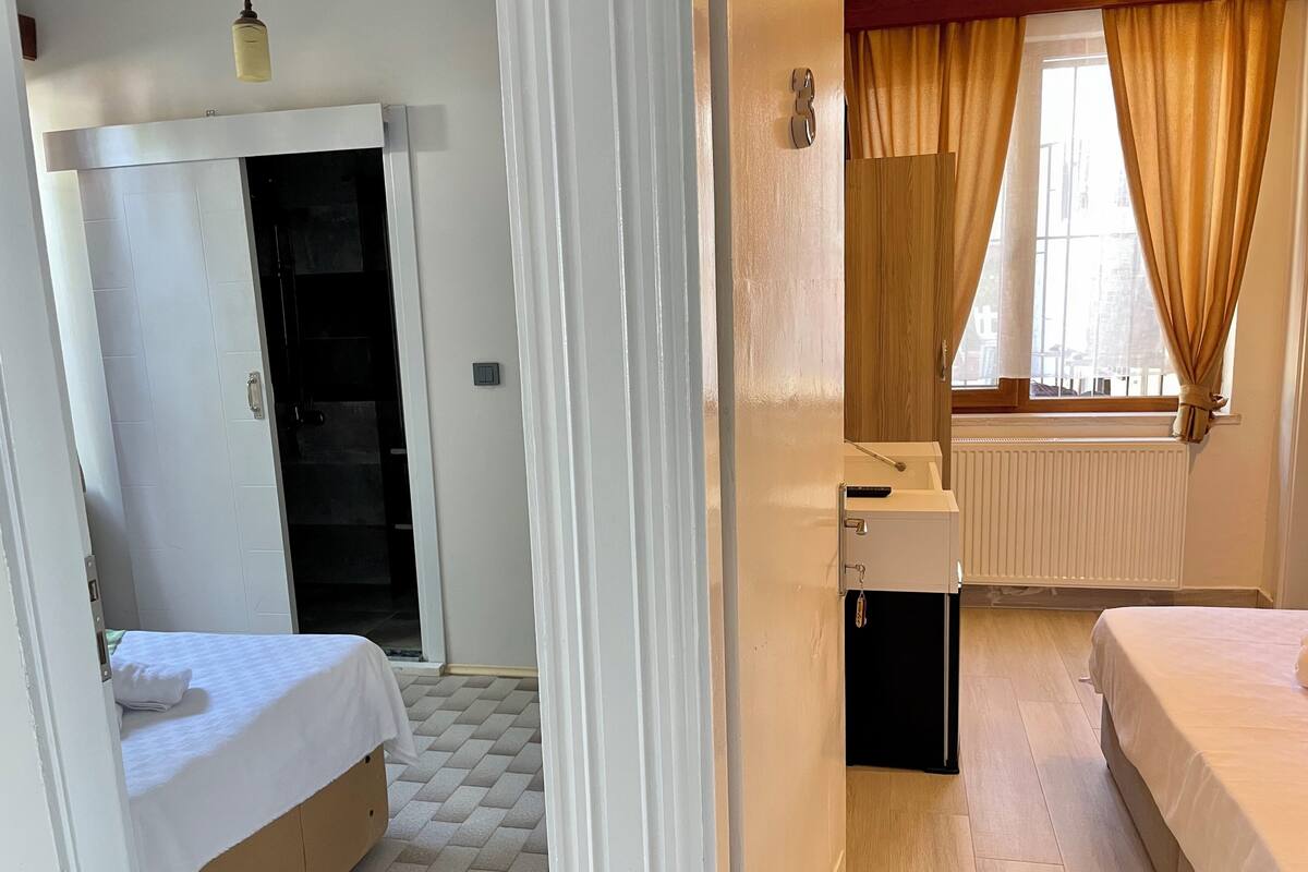 A hotel room with a bed, a small desk, a wardrobe, and a window with curtains.