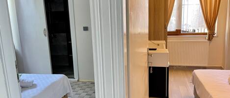 A hotel room with a bed, a small desk, a wardrobe, and a window with curtains.