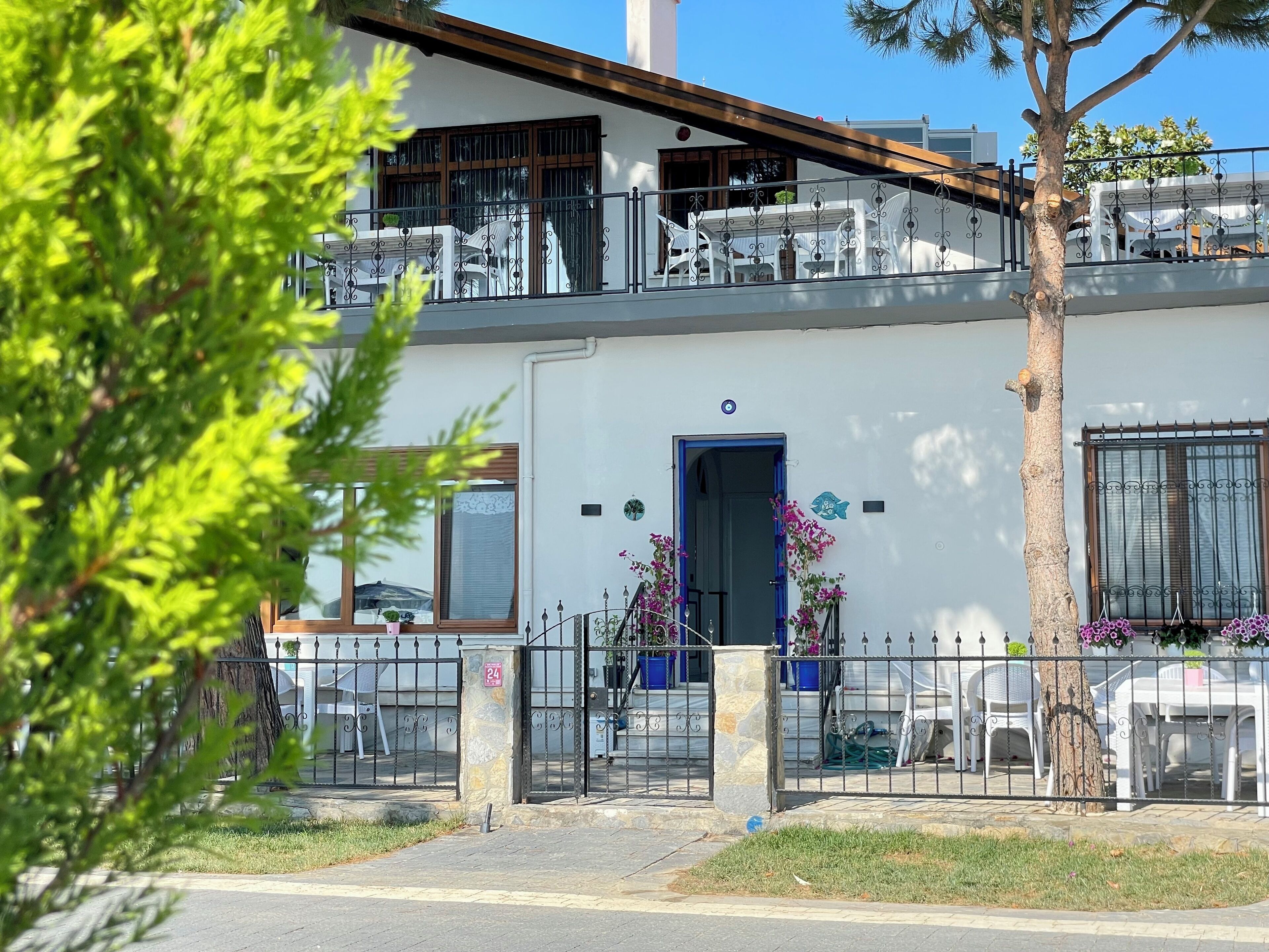 A two-story building with a balcony, a blue door, and a stone pillar.