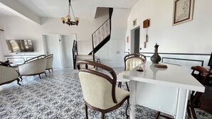 A dining area with a white table, two chairs, a chandelier, and a patterned floor. - Villa Ece Pension (Erdek)