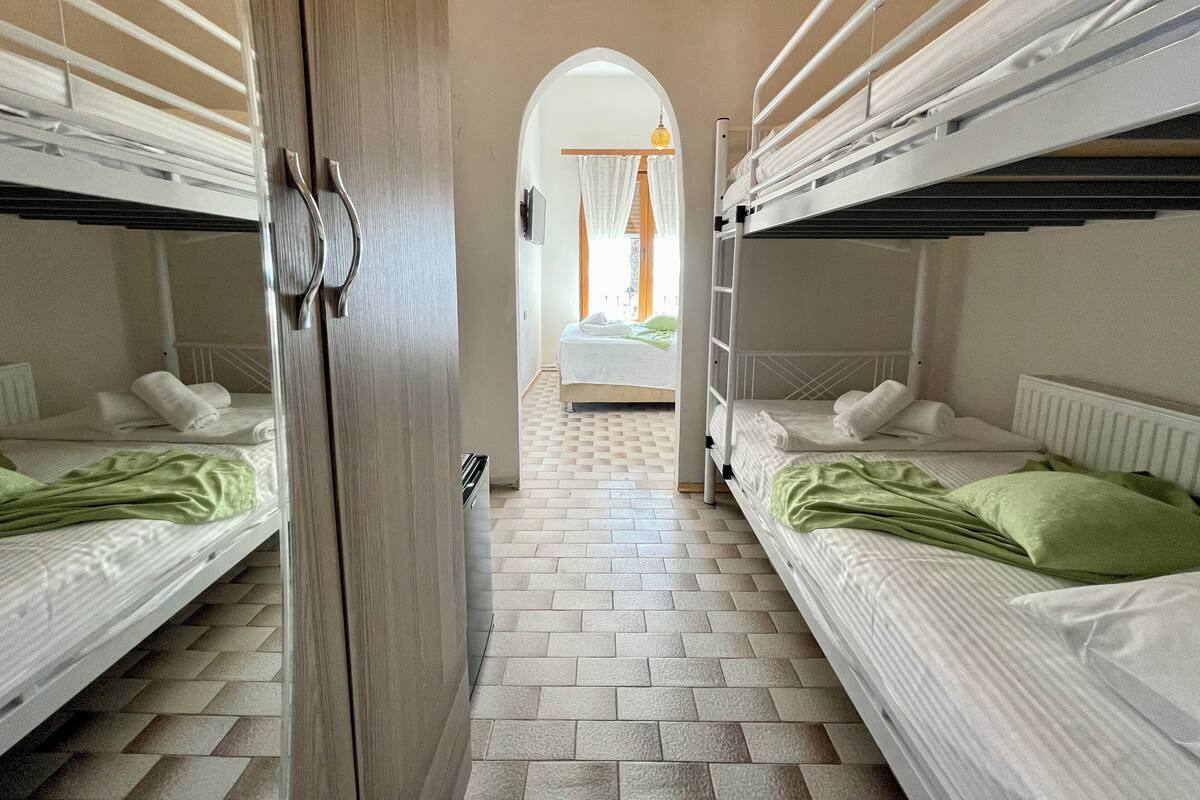 A corridor with bunk beds on either side, leading to a room with a bed and a window.