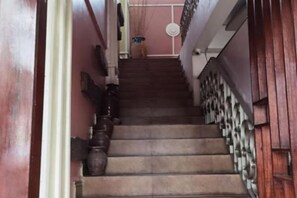 Un escalier avec une rampe en bois et un vase placé sur le côté gauche.
