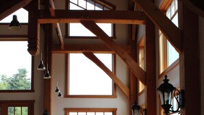 A dining area with a wooden table and chairs, large windows with a view, and hanging pendant lights. - Bay Bluff Haven:  Ocean, Glacier, & Wildlife View (Homer)