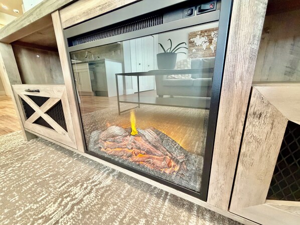 A fireplace with a glass enclosure, a wooden cabinet to the left, and a world map decoration on the wall.