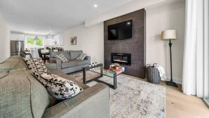 A modern living room with a sofa, coffee table, and fireplace. - NEW 797 Lakeshore rd Paradise (Selkirk)