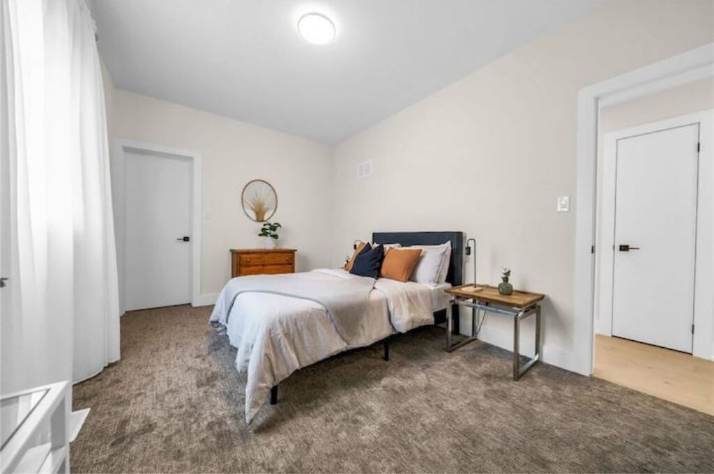 Un dormitorio con cama, mesita de noche, cómoda y una puerta.