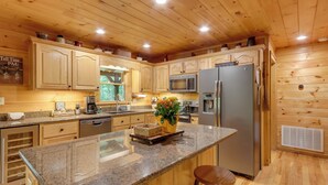 Cucina con mobili in legno, piani di lavoro in granito, elettrodomestici in acciaio inossidabile e un'isola centrale con sgabelli.