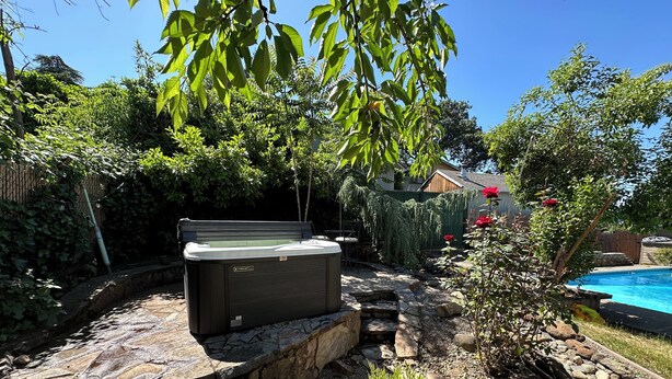 En baghave med jacuzzi, swimmingpool og en stenbelagt sti.