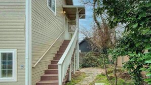 Une maison avec un chemin de pierre menant à un escalier en bois.