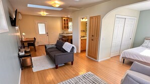 A spacious living area with a sofa, a dining table, and a kitchen in the background. - Bring everyone together while enjoying the privacy of three separate living spaces. This unique Medford retreat features a spacious main home, two private guest homes, a seasonal pool, hot tub, fully equipped kitchens, and room for the whole family. (Medford)