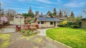 A two-story house with a front porch, a driveway, and a well-maintained lawn. - Bring everyone together while enjoying the privacy of three separate living spaces. This unique Medford retreat features a spacious main home, two private guest homes, a seasonal pool, hot tub, fully equipped kitchens, and room for the whole family. (Medford)
