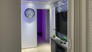 Un couloir au design moderne, agrémenté d’une horloge murale, d’une assiette décorative et d’une console sur laquelle sont disposées des plantes.