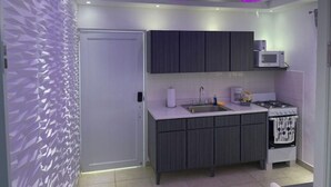 Une cuisine moderne avec des meubles de couleur sombre, un four à micro-ondes, une cuisinière et un mur décoratif orné de motifs géométriques.