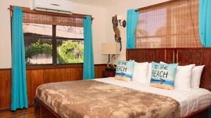 Een slaapkamer met een groot bed, een houten hoofdbord en twee kussens met strandmotieven.